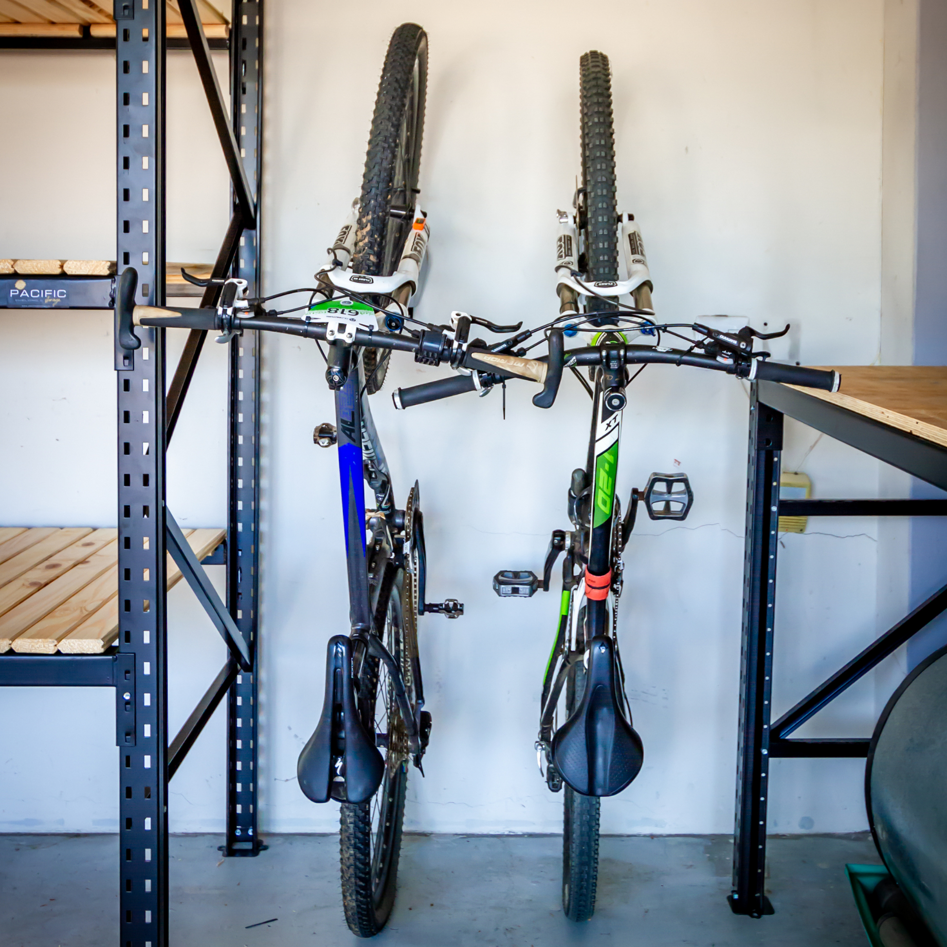 Two bicycles standing upright with wall hooks